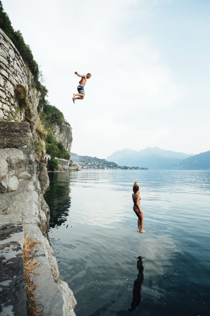 Man and woman jump off of cliff into ocean