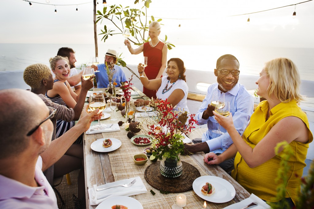 People gather around outdoor dinning table for a toast